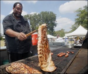 Quinsey Hammond of Toledo flips a slab of ribs he’s cooking for attendees at the festival on the University of Toledo Scott Park campus.