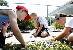 Trey Tuttamore, 10, left, Austin Fry, 9, center, and Mya Tuttamore, 9, right, make a tie-dye headbands during an afternoon of outdoor activities with the Fun Bus of the YMCA in Memorial Park in Pembervillle.