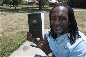 Street preacher Charles ‘Slim' Lake displays a copy of ‘The Now Testament: Featuring the New Gospel,' which he wrote while in prison.