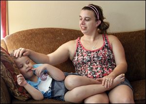 McKenna May sits with mother, Whitney Hughes. McKenna finished chemotherapy treatment for leukemia on June 25. A family dispute had led to the refusal of a Make-A-Wish Foundation grant.