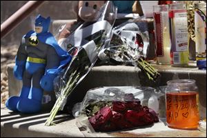 Candles, flowers, and a Batman figure are shown at a memorial. Twelve people were killed and dozens were injured in a shooting attack early Friday at the packed theater during a showing of the Batman movie, 