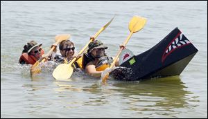 United States Navy SEAL Team 10 member Eric Bradley, center, is flanked by his parents, Bob Bradley, left, and Betsy Bradley, as they paddle their sinking boat in the cardboard boat race. The former La Salle native was home on leave visiting his parents and was drafted Into the boat races.