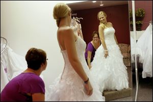Morghan Spychalski and Paige LaCourse laugh as Spychalski tries on a Moonlight wedding dress at Dream Designs Bridal Outlet in Toledo.