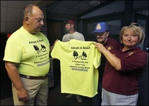 Phil Wesley, left, and Patti Wenski hold one of the shirts for volunteers such as Ms. Wenski and Ralph Wenski, center. They were at Our Lady of Mount Carmel last week.