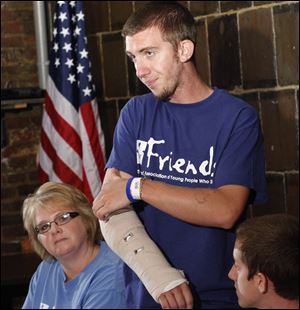 Gage Hankins points out where he was shot while his mother Sarah Hankins, left, listens during a press conference today to discuss Gage Hankins' injury in the Colorado theater shooting.