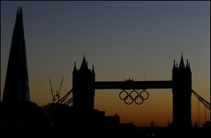 Tower Bridge with Olympic rings is silhouetted as the sun sets Monday in London. The summer Olympics in London starts on Friday.