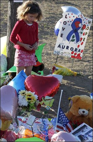 Serenity Brydon, 7, from Aurora, looks at a memorial near the the Century 16 movie theater Sunday in Aurora, Colo. Twelve people were killed and dozens were injured in a shooting attack early Friday at the packed theater during a showing of the Batman movie, 