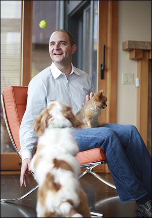 Aaron Easterly of Rover.com holds his dog Caramel as he pet sits Charlie. The site has about 10,000 hosts in more than 40 states.