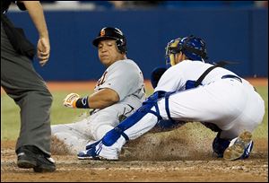 Miguel Cabrera, left, scores past catcher Jeff Mathis' tag in the eighth inning, but the Tigers lost 8-3 on Friday night in Toronto.
