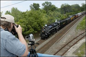 Matt Snell of Cincinnati films and photographs the Nickel Plate Road 765 steam locomotive as it makes its way under Miami Street toward Maumee. Mr. Snell was among a few dozen who gathered to watch.
