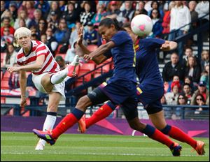 The United States' Megan Rapinoe, left, shoots past a pair of Colombian defenders during the first half to score. The United States defeated Colombia 3-0 to guarantee a spot in the quarterfinals.