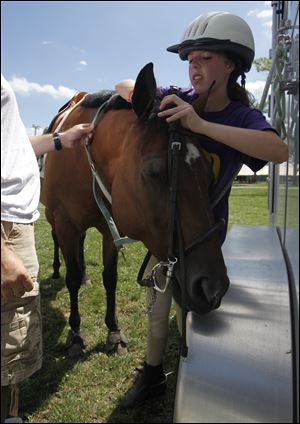 Gabby Dugger, 15, of Perrysburg puts an English bridle on Annie at the Wood County Fair. The teen competes in both English and Western competitions.