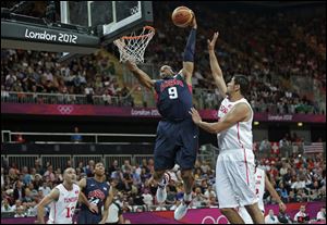 The United States' Andre Iguodala (9) dunks over Tunisia's Mohamed Hadidane during a 110-63 rout for the Americans.