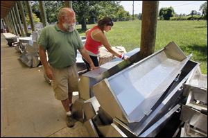 Tom Lingeman, art professor at the University of Toledo, and UT student Kristin Evans look at stainless-steel hoods that thieves left alone at UT's Center for Sculptural Studies. Someone recently cut through a fence and stole four of the hoods, originally used for cadavers.