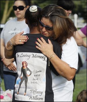 Demisha Wilborn, left, is hugged by Trina Oviedo-Frankum 
during Thursday’s vigil at the Violence Against Women Memorial
Rock at the Sanger Branch Library in Toledo. Ms. Wilborn’s daughter, Tiffany, died after being stabbed in March. Ms. Oviedo- Frankum’s daughter, Leandra, was killed late last month.