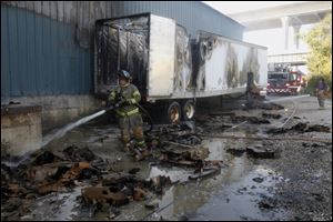 Firefighters douse debris with water after a semi truck trailer caught in the 1500 block of Water Street Wednesday.