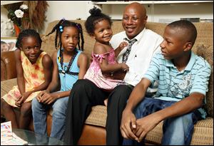 Roy Jenkins of North Toledo is raising not only his daughter R'Zhanai, on his lap, but also three of his grandchildren. Seated on the couch from left are granddaughters Doreanna, 8, and Heaven, 10, and grandson JayVon, 13.
