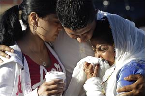Amardeep Kaleka, son of the president of the Sikh Temple of Wisconsin, center, comforts members of the temple in Oak Creek, Wis., where a gunman killed six people a day earlier, before being shot and killed himself by police.