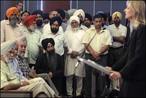 Members of the Sikh Temple of Wisconsin listen to FBI Special Agent in Charge, Teresa Carlson, during a news conference in a municipal building in Oak Creek, Wis.