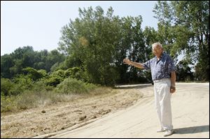 Howard Pinkley, of Point Place, points out the future location of his envisioned restaurant and lodge along the mile-long pathway that he is also planning to build on the forested peninsula adjacent to the Toledo Yacht Club.