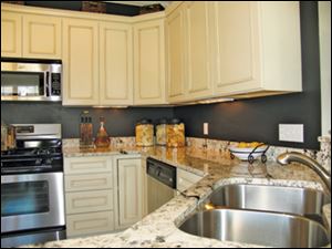 The kitchen’s antiqued white cabinets and dark walls make a perfect backdrop for the beautifully veined granite countertop.