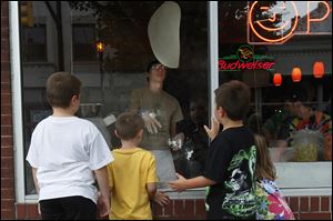 Konnor Sager, 8, of Millbury, left, J.J. Short, 8, center left, Jax Sager, 6, center right, and Holly Short, 6, watch as Jeffrey Schwietzer tosses dough in the window of J&G Pizza Place in downtown Sylvania. 
