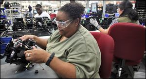 Awilda Isaac, left, works on a printer being assembled at Datacard Co. in Minnetonka, Minnesota. The company, which recently moved a production line from a plant in Malaysia to Minnetonka, is among several in the state that have moved manufacturing operations back to the States.