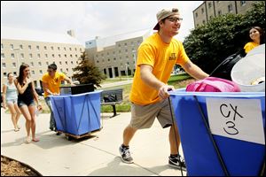 Logan Bowling, a first-year resident orientation guide, helps move a freshman into her dormitory at the University of Toledo. Rockets have until Sunday to pay their bills in full or make arrangements.