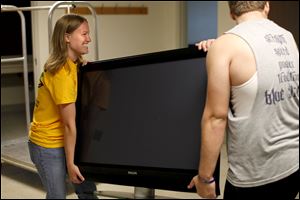 Hali Wilcox, an orientation leader, and freshman Christopher Graham move a television set into Mr. Graham's dorm room at the University of Toledo. Meanwhile, at Bowling Green State University, the payment deadline for students was Wednesday.