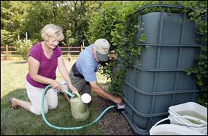 Jim and Joanne Bucklew fi ll their watering can from a rain barrel.