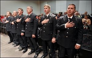 Toledo firefighters being promoted, from left, Captain Bryce D. Blair, Jr. (to battalion chief), Lieutenants Mike and Mark Benadum (both brothers to captains), and privates Robert Swartz, Matt Viertlbeck, and Jeremy J. Vedra (all to lieutenant), stand for the Pledge of Allegiance during the Toledo Fire and Rescue Department promotions ceremony at One Government Center in Toledo.