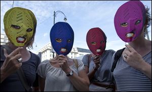 Supporters of the punk band Pussy Riot hold up face masks depicting group members in front of the Russian delegation in Brussels.