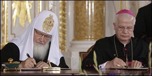 Patriarch Kirill, left, of the Russian Orthodox Church, and Archbishop Jozef Michalik sign the agreement in Warsaw.