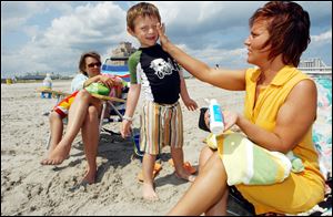 Bernadine Boyce, of Allentown, Pa., applies sunscreen to Bruno Barber, 5, of Atlantic City, as mom, Natalia Barber, watches in Atlantic City, N.J. Sun damage is the No. 1 threat to skin care.