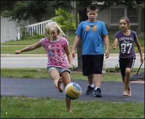 Kamara Foster, 7, shows her form during a game of kickball in the yard of an Eastfield Drive home in Maumee while Michael Pacer and Haleigh Crouch, both 9, watch. The youngsters Tuesday were enjoying their last day of unfettered summer fun: Today is the first day of school in Maumee.