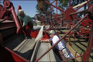 Curtis Johnson, left, and Dennis Wyse install canvas in a 1957 International pull-type combine as they get ready for the Fulton County Fair. Mr. Johnson says ‘a core of guys … help me find stuff.'