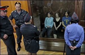 Nadezhda Tolokonnikova, right, Yekaterina Samutsevich, left, and Maria Alekhina, center, members of feminist punk group Pussy Riot seen behind a glass wall at a court in Moscow, Russia, on Aug. 17.