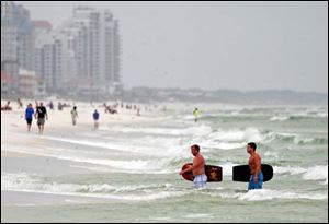 Tourists wade out of the rough water caused by Tropical Storm Isaac.