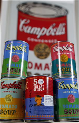 Limited-edition tomato soup cans, with art and sayings by the late Andy Warhol, sit before an original 1960s painting of  a Campbell's can. The painting hangs in the company boardroom in New Jersey.