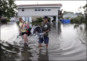 Tony Rodriguez, right, carries baby daughter Nicole as he and wife Jodi Clelland leave their flooded home Friday in the aftermath of Hurricane Isaac in Slidell, La.
