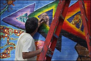 Bob Garcia, an Organization of Latino Artists member, touches up a mural on the building at the corner of Jervis and Broadway in Toledo.