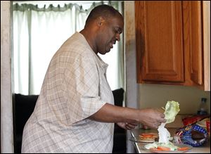 Greg Cunningham puts a piece of lettuce on a meatless cheeseburger at his home in Toledo.