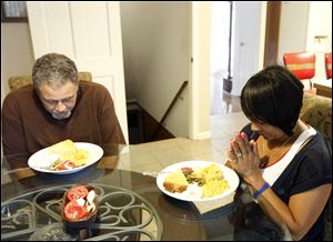 Vernon Hague, left, and wife L'Tanya Hague pray before tucking into their vegetarian dinner of green beans, fried corn, potatoes, and macaroni cheese at their home.