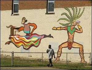 A man walks past images of dancers painted this summer by BGSU students.