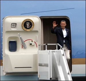 President Obama waves from the door of Air Force One as he lands Sunday at Toledo Express Airport.