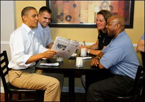 President Barack Obama looks at a copy of the Blade while sitting in Rick's City Diner in Toledo  with Daniel Schlieman, back left, Heather Finrock, and James Fayson, right.