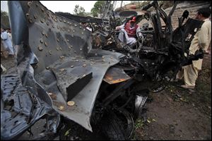 A Pakistan rescue worker looks at a vehicle targeted by terrorists in Peshawar, Pakistan on Monday, Sept. 3, 2012.  A suicide bomber rammed a car filled with explosives into a U.S. government vehicle in northwestern Pakistan Monday.