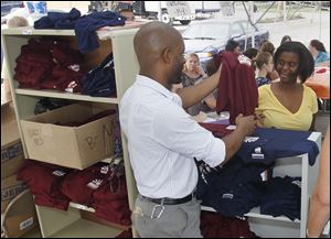 Domonique Glover, an algebra teacher for Horizon Science Academy, gives sophomore Lia Bias a uniform shirt during orientation in the parklng lot of DeVeaux Village.