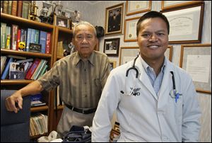 Dr. Antonio Paat, left, one of the earliest Filipinos to settle in Toledo, visits his son Dr. Richard Paat in the younger Dr. Paat's office in Maumee. 