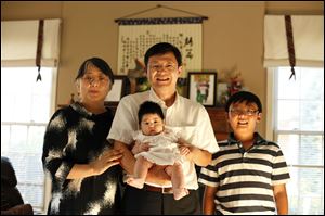 Sam Yang, holding  daughter Lydia, is joined by his wife, Ying Li, and son Evan in their Perrysburg home. Mr. Yang, a research and development manager at First Solar Inc., would like to see more facilities in the area for Chinese and Chinese-Americans.